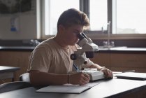 Teenage boy experimenting on microscope in laboratory at university — Stock Photo