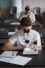 Adolescente experimentando microscópio em laboratório na universidade — Fotografia de Stock