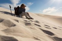 Caminhante masculino olhando através binocular na areia no deserto — Fotografia de Stock