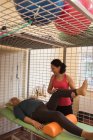 Жінка-фізіотерапевт дає масаж коліна старшому пацієнту в будинку престарілих — стокове фото