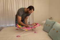Pai brincando com o bebê filho na cama do bebê em casa . — Fotografia de Stock