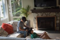 Father and son using virtual reality headset in living room at home — Stock Photo