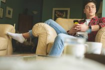 Uomo che utilizza il telefono cellulare mentre si rilassa in poltrona in soggiorno a casa . — Foto stock