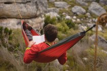 Escursionista sdraiato in amaca leggere romanzo in una giornata di sole — Foto stock