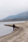 Homem e seu cão de estimação andando na margem do rio — Fotografia de Stock