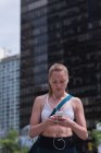 Молодая спортсменка пользуется мобильным телефоном на улице — стоковое фото