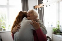 Эмоциональная бабушка и внучка обнимают друг друга в гостиной — стоковое фото