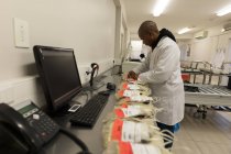 Laboratory technician analyzing plasma bags in blood bank — Stock Photo