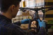 Rear view of man repairing bicycle shock absorber in shop — Stock Photo