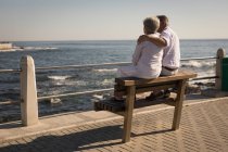 Senior couple sitting on bench near sea side at promenade — Stock Photo