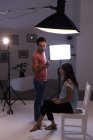 Fotógrafo do sexo masculino gravando uma entrevista usando gravador de voz em estúdio de fotografia — Fotografia de Stock