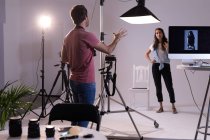 Photographe masculin et mannequin féminin interagissant les uns avec les autres en studio photo — Photo de stock