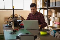 Mechaniker mit Laptop auf Schreibtisch in Werkstatt — Stockfoto