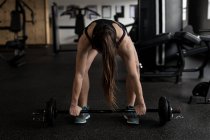 Фигуристка, поднимающая штангу в фитнес-студии — стоковое фото