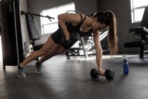 Beautiful woman doing push ups on dumbbells in fitness studio — Stock Photo