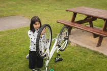 Молода дівчина ремонтує велосипед в саду — стокове фото
