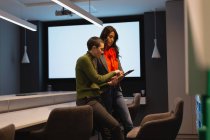 Коллеги по бизнесу обсуждают за цифровым планшетом в конференц-зале офиса — стоковое фото