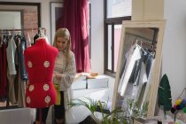 Modedesignerin kleidet Schaufensterpuppe im Modestudio — Stockfoto