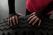 Sección media de la mujer haciendo ejercicio con el neumático en el gimnasio - foto de stock