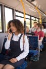 Jovem mulher viajante falando no celular enquanto viaja em ônibus moderno — Fotografia de Stock
