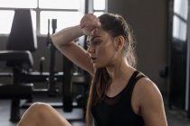 Young woman wipes sweat after workout in fitness studio — Stock Photo