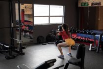Visão traseira da mulher levantando barbell no estúdio de fitness — Fotografia de Stock