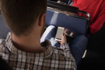 Sobrecarga del viajero masculino que utiliza el teléfono móvil mientras viaja en autobús moderno - foto de stock