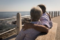 Senior couple sitting on bench with arms around at promenade — Stock Photo