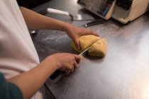 Männerbäcker schneidet Teig in Bäckerei — Stockfoto