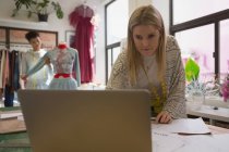 Designer de moda bonita usando laptop no estúdio de moda — Fotografia de Stock