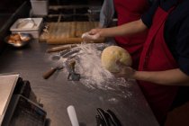 Baker putting white flour on dough in bakery — Stock Photo
