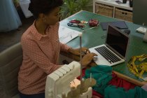 Créateur de mode utilisant un ordinateur portable sur le bureau dans un studio de mode — Photo de stock
