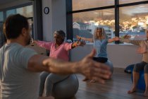 Entrenador y grupo de mujeres mayores realizando yoga en centro de yoga - foto de stock
