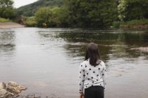 Vue arrière de la fille debout près de la rivière — Photo de stock