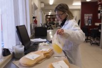Лабораторний технік тримає плазмові пакети в банку крові — стокове фото