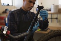 Attentive man repairing bicycle seat in workshop — Stock Photo