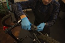 Joven reparando bicicleta en taller - foto de stock