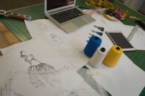 Ескіз, нитка, ноутбук тримаються на столі в студії моди — стокове фото