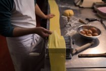 Close-up of baker using machine for preparing pasta in bakery — Stock Photo