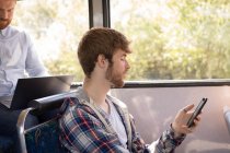 Смарт-чоловічий комп'ютер використовує мобільний телефон під час подорожі в сучасному автобусі — стокове фото