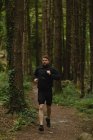 Jeune homme jogging au sentier forestier — Photo de stock
