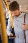 Comutador masculino inteligente usando telefone celular enquanto viaja em ônibus moderno — Fotografia de Stock