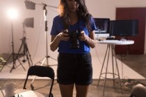 Female model looking at digital camera in photo studio — Stock Photo