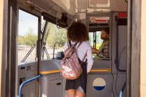 Задний вид женщины, берущей билет у водителя в современном автобусе — стоковое фото