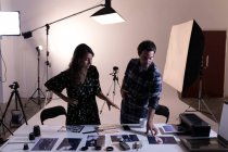 Fotógrafo masculino e feminino discutindo fotografias em estúdio de fotografia — Fotografia de Stock