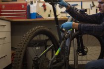 Молодой человек регулирует сиденье велосипеда с гаечным ключом в мастерской — стоковое фото