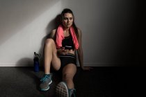 Красивая женщина с помощью мобильного телефона в фитнес-студии — стоковое фото