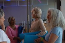 Група літніх жінок, що взаємодіють один з одним в центрі йоги — стокове фото