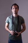 Male photographer standing with digital camera in photo studio — Stock Photo