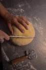 Baker coupe une pâte sur le comptoir dans la boulangerie — Photo de stock